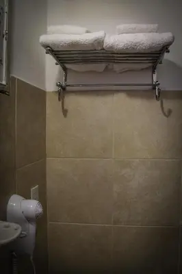 a bathroom with a toilet and towels on a rack at Hotel Menossi in Río Cuarto