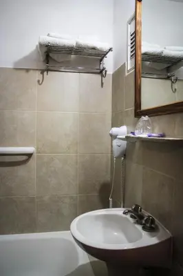 a bathroom with a sink and a tub and a mirror at Hotel Menossi in Río Cuarto
