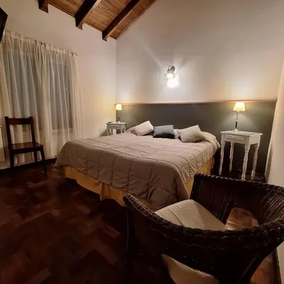 a bedroom with two beds and two chairs at Hostal La Merced in Villa General Belgrano