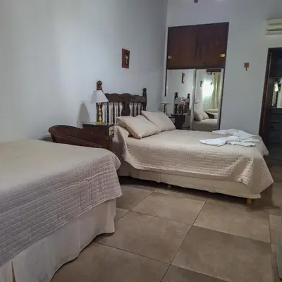 a bedroom with two beds and a mirror at Hostal La Merced in Villa General Belgrano