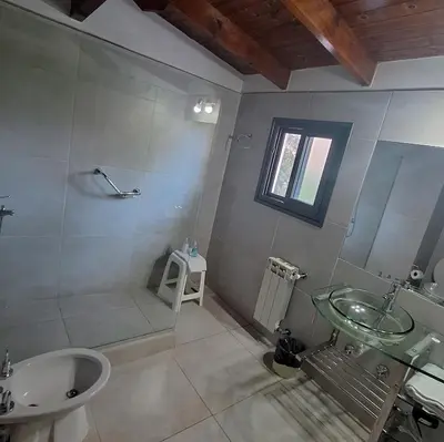 a bathroom with a sink and a shower with a glass sink at Hostal La Merced in Villa General Belgrano