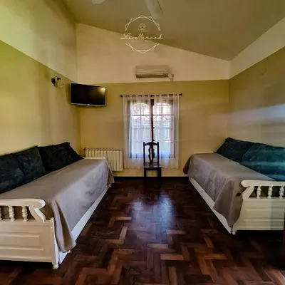 a bedroom with two beds and a tv on the wall at Hostal La Merced in Villa General Belgrano
