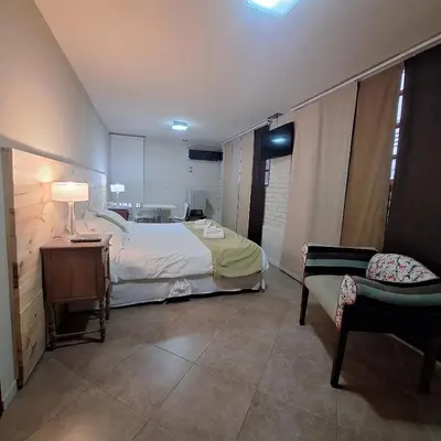 a bedroom with a bed and a chair in a room at Hotel Antiguo Camino in Villa General Belgrano