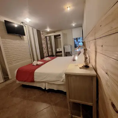 a bedroom with a bed and a tv on a wall at Hotel Antiguo Camino in Villa General Belgrano