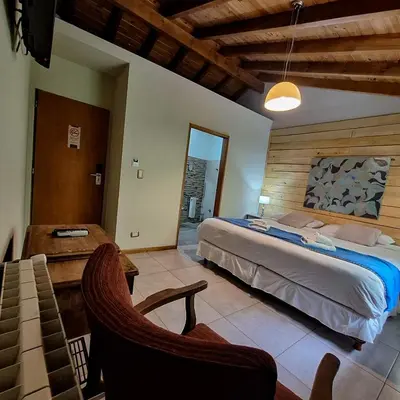 a bedroom with a bed and a chair in a room at Hotel Antiguo Camino in Villa General Belgrano
