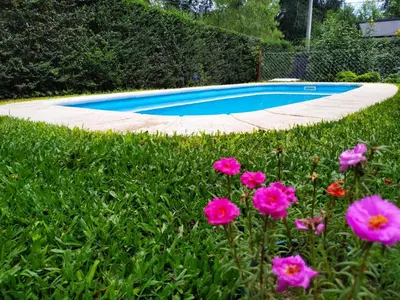 a swimming pool in a yard with pink flowers at Rincón Sereno in Villa General Belgrano
