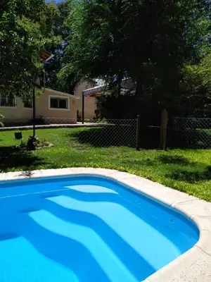a blue swimming pool in a yard with a house at Rincón Sereno in Villa General Belgrano