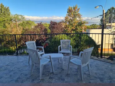 four white chairs and a table on a patio at Cabañas Las Pencas in Mina Clavero