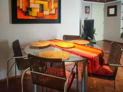 a dining room table with chairs and a table with a red and orange blanket at Las Tejas in Cordoba