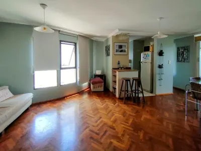a living room with a wooden floor and a kitchen at Las Tejas in Cordoba