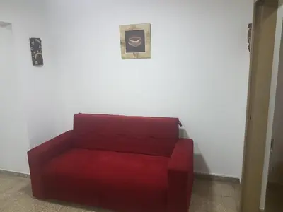 a red couch sitting next to a white wall at Departamento a estrenar excelente ubicacion, 1 cuadra de la terminal in Cordoba