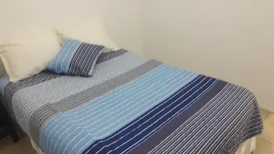 a bed with blue and white sheets and two pillows at DPTO ALTA CORDOBA in Cordoba
