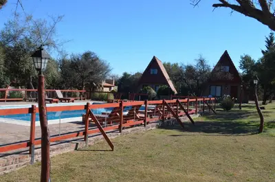 a resort with a swimming pool and a house at Cabañas Ayres del cerro in Merlo
