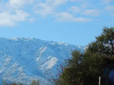 a snow covered mountain in the distance with a tree at Cabañas Ayres del cerro in Merlo