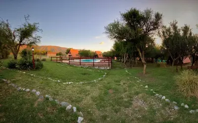a garden with a pool and trees and a fence at Cabañas Ayres del cerro in Merlo