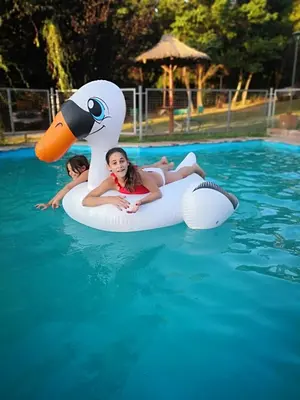 two girls riding on an inflatable duck in the water at Cabañas Dalga Inn in Merlo