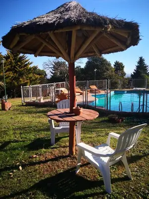 a table and chairs under an umbrella next to a pool at Cabañas Dalga Inn in Merlo