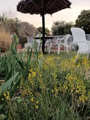 a garden with white chairs and an umbrella and flowers at Cabañas Dalga Inn in Merlo