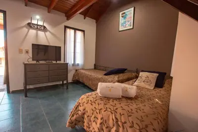 a bedroom with two beds and a flat screen tv at Cabañas Dalga Inn in Merlo