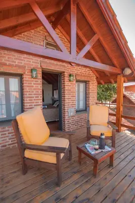 two chairs and a table on a wooden deck at Cabañas Dalga Inn in Merlo