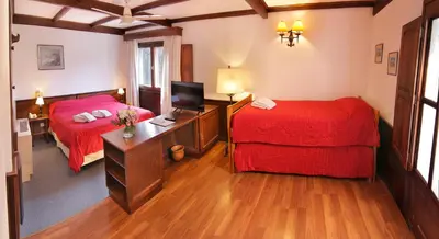 a room with two beds and a desk with a television at Bremen Hotel & Spa in Villa General Belgrano