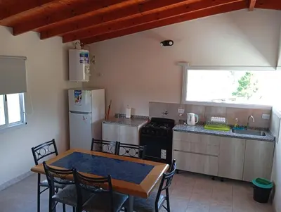 a kitchen with a table and a refrigerator and a stove at Cabañas PAIGÜEN in Villa Yacanto