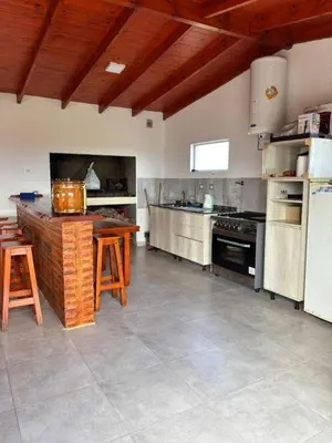 a large kitchen with a table and a refrigerator at Cabañas PAIGÜEN in Villa Yacanto