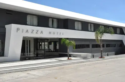 a hotel with palm trees in front of a building at Piazza Hotel in Villa Carlos Paz