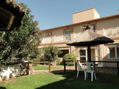 a patio with a table and chairs and an umbrella at Casa Nostra Hotel in Villa Carlos Paz