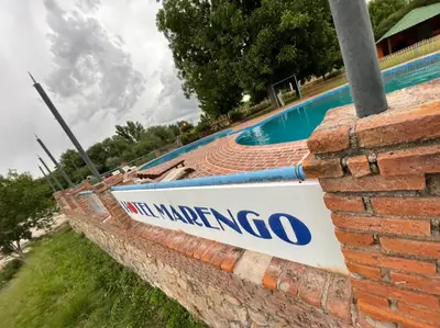 a sign on a brick wall next to a swimming pool at Hotel Marengo in Mina Clavero