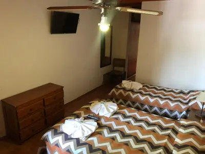 a room with two beds and a dresser in it at Hotel Marengo in Mina Clavero