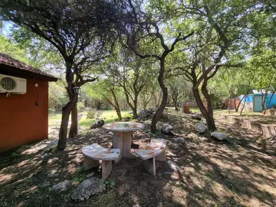 a picnic table and chairs in the shade of trees at Cabañas Wayramuyu in Merlo