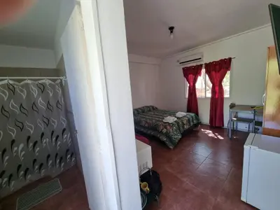 a bedroom with a bed and red curtains in a room at Cabañas Wayramuyu in Merlo