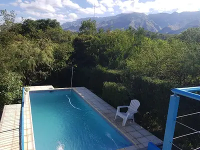 a blue swimming pool with a chair at Cabañas Wayramuyu in Merlo
