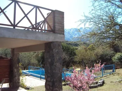 a bridge over a swimming pool with mountains in the background at Cabañas Wayramuyu in Merlo
