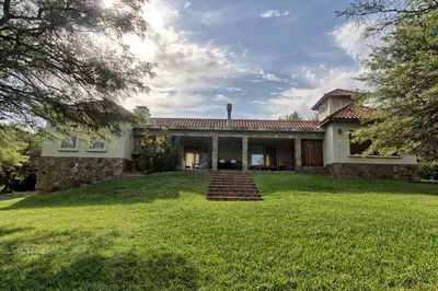 an exterior view of a house with a grass yard at Casas de Campo Henin in Villa General Belgrano