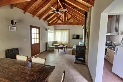 a living room with a dining room table and a kitchen at Casas de Campo Henin in Villa General Belgrano