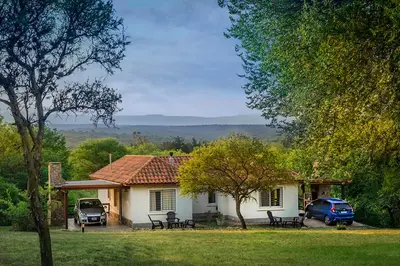 a house with two cars parked in front of it at Casas de Campo Henin in Villa General Belgrano