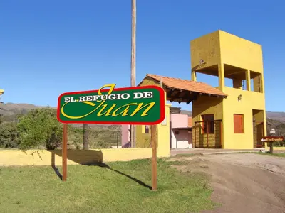 a sign in the grass in front of a building at Cabañas El Refugio de Juan in Mina Clavero