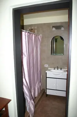 a bathroom with a sink and a pink shower curtain at El Rincón del Molle in Merlo