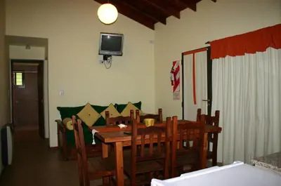 a dining room with a table and a tv on the wall at El Rincón del Molle in Merlo