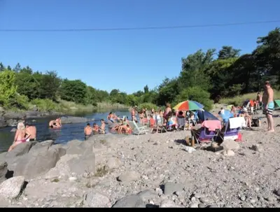 a group of people on a beach near a river at Ensueño in Santa Rosa de Calamuchita