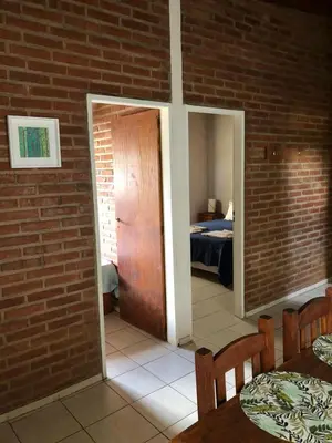 a room with a brick wall with a door and a bedroom at Cabañas La Querencia 2 dormitorios in Villa Cura Brochero