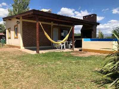 a small house with a hammock in front of it at Cabañas La Querencia 2 dormitorios in Villa Cura Brochero