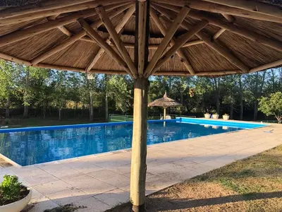 a wooden umbrella next to a swimming pool at Cabañas La Querencia 2 dormitorios in Villa Cura Brochero