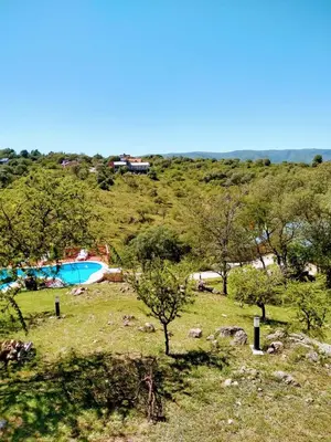 a field with trees and a swimming pool on a hill at CAMINITOS in Villa General Belgrano