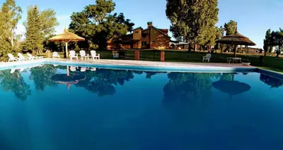 a swimming pool with blue water in front of a house at Casa de campo La Querencia in Villa Cura Brochero