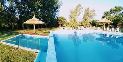 a large swimming pool with umbrellas and chairs next to it at Casa de campo La Querencia in Villa Cura Brochero