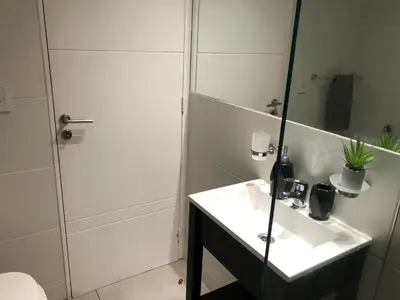 a bathroom with a white sink and a shower at LitStay Brasil con cochera, pileta y asadores in Cordoba