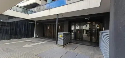 a building with glass doors and a trash can at LitStay Brasil con cochera, pileta y asadores in Cordoba
